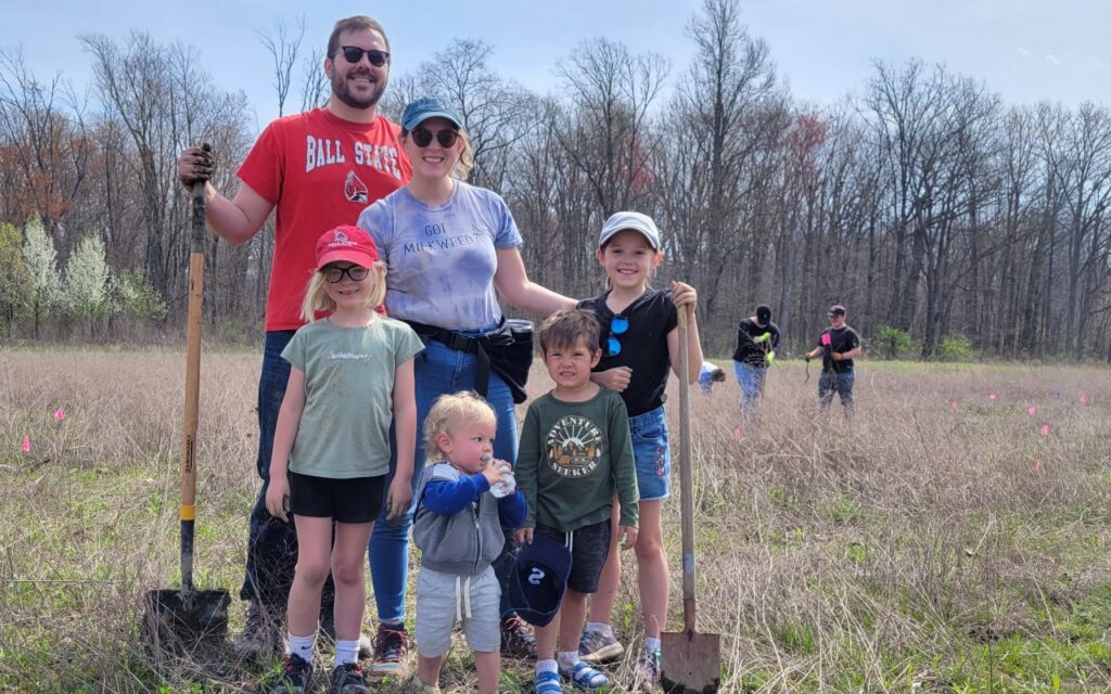 Family poses with shovels at 2022 Earth Day Tree Planting